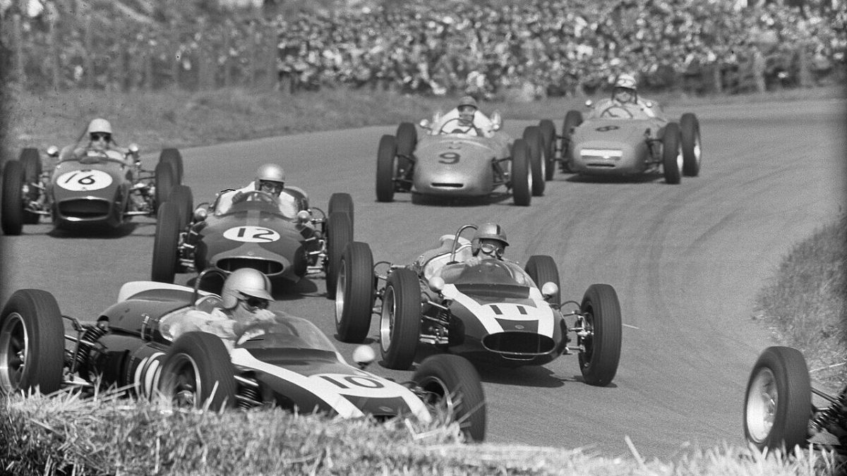 Vintage Formula 1 cars racing on the Zandvoort circuit with spectators lining the track