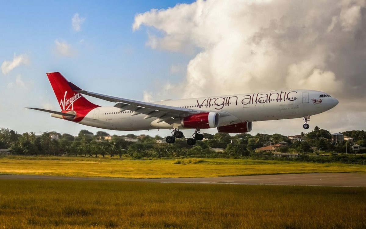 Virgin Atlantic Airbus A330 aircraft landing over green fields with clouds in sky