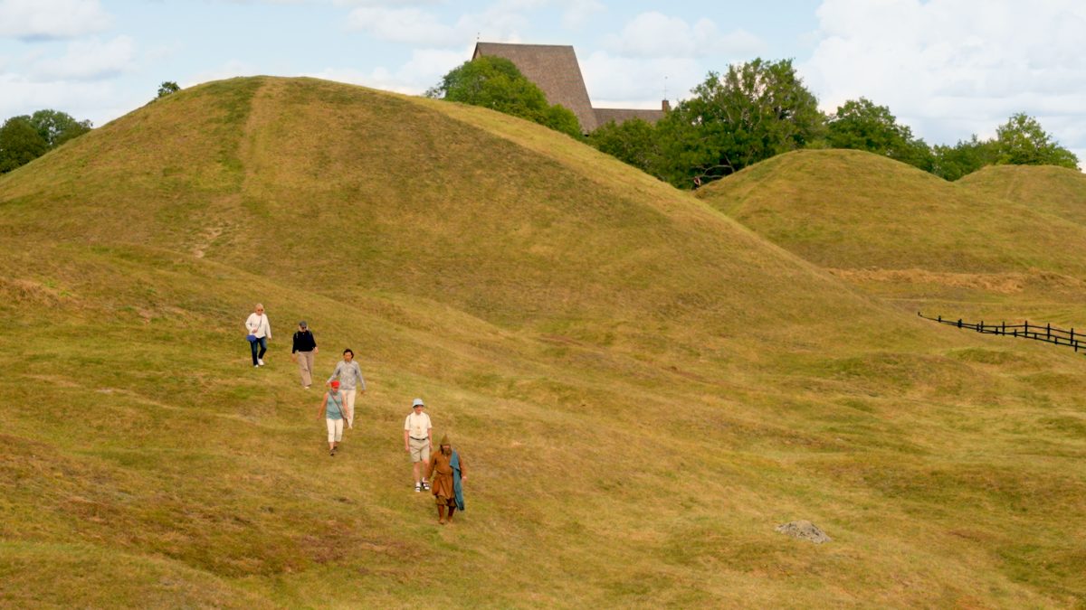 Visitors exploring the grassy mounds of Gamla Uppsala, Sweden's historic archaeological site