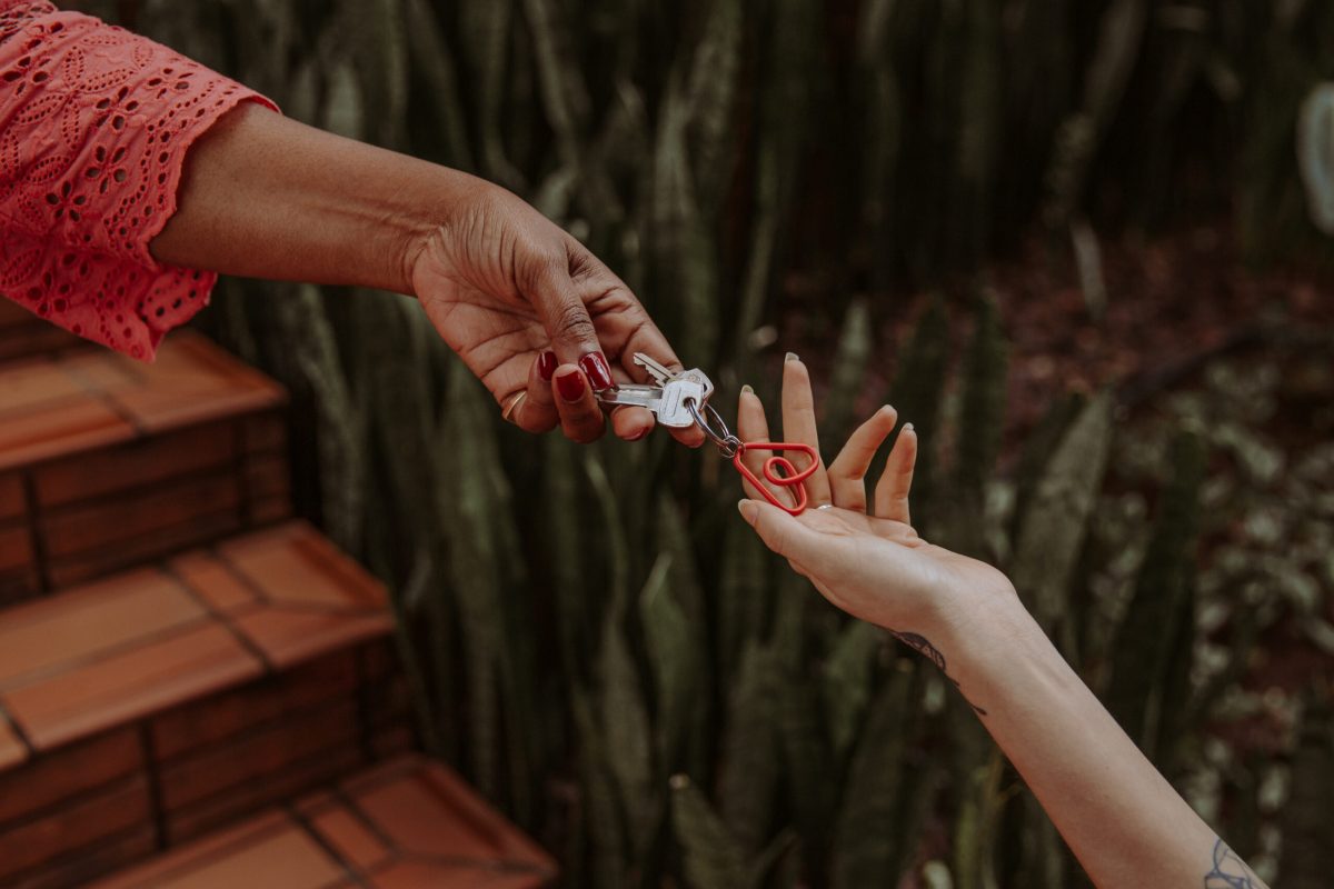 Two hands exchanging a wedding ring outdoors near brick and ivy