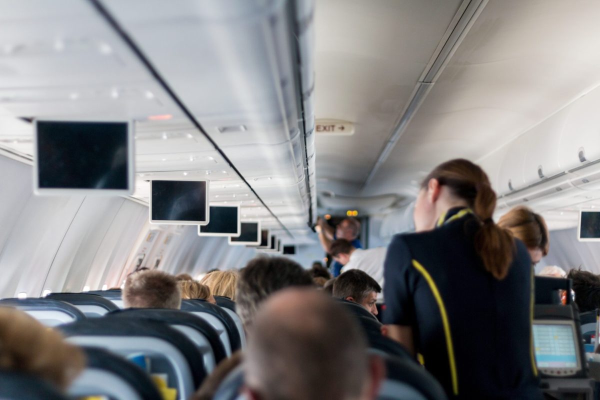 Interior of commercial airplane cabin with passengers seated in rows during flight