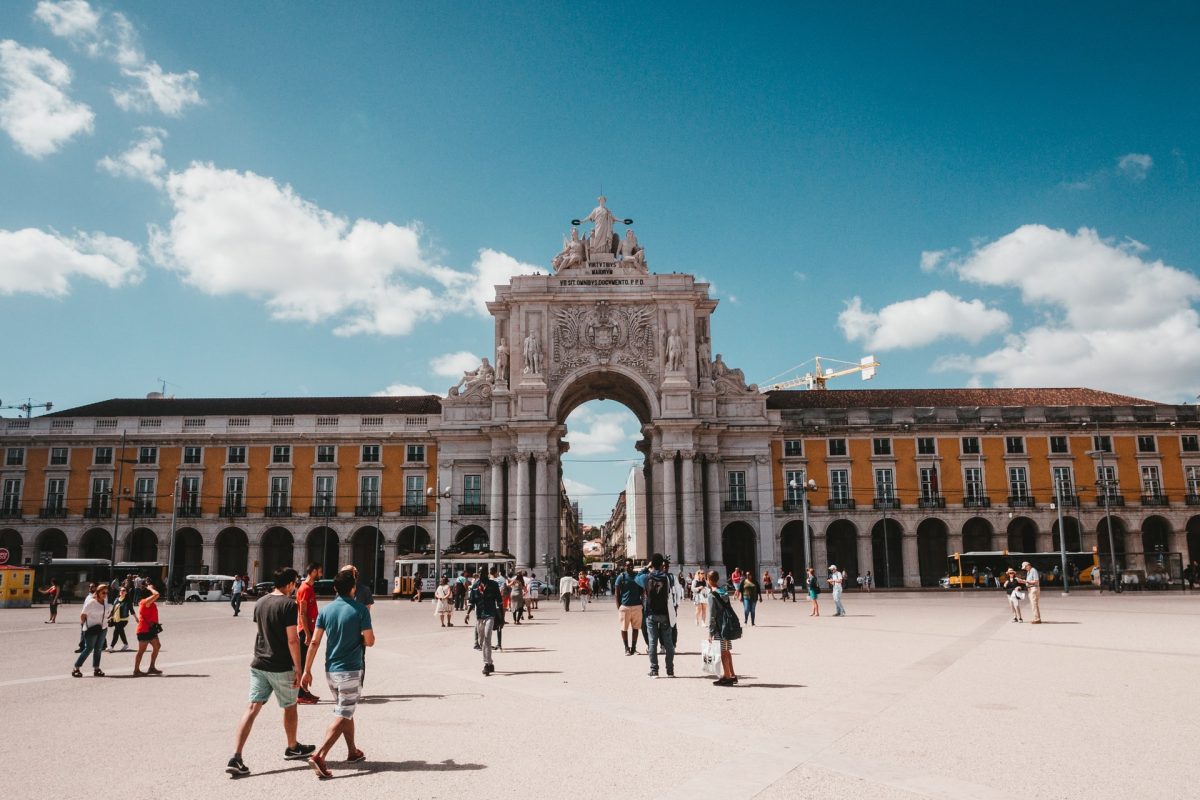 Lisbon's Rua Augusta Arch framed by bustling pedestrian plaza and sunny sky.