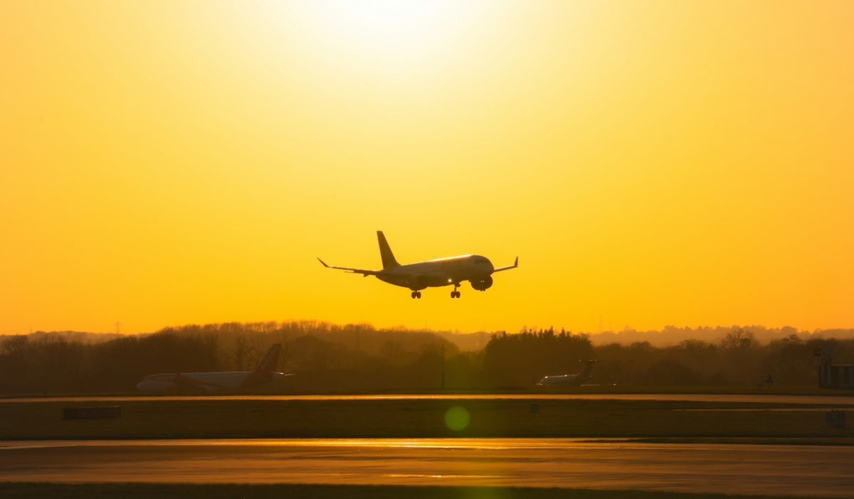 Commercial airplane landing at sunset with golden sky and runway reflection