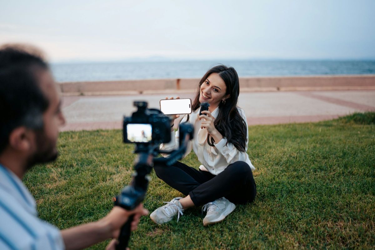 Woman being interviewed on camera with coastal landscape and beach in background