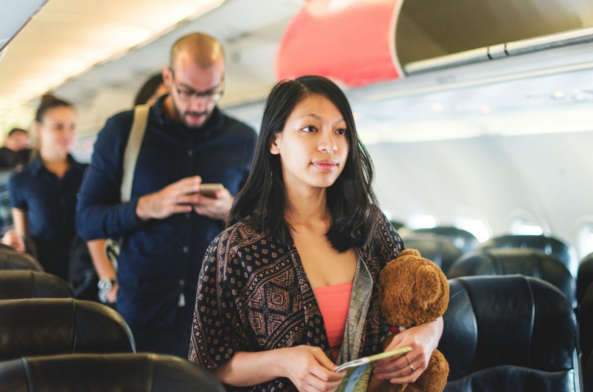 Woman holding a teddy bear inside an airplane cabin during flight