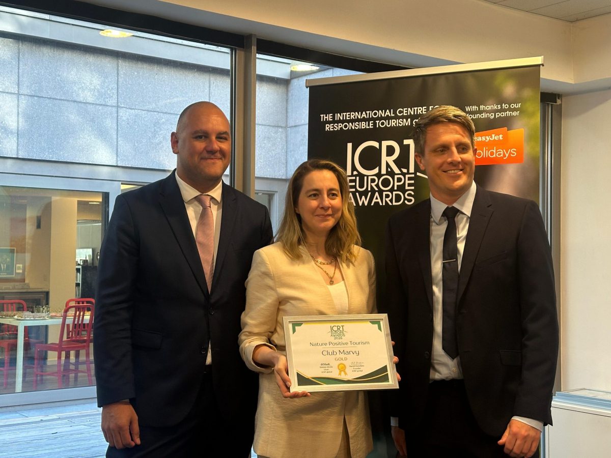 Woman holding award certificate between two men at ICCR Europe Awards ceremony