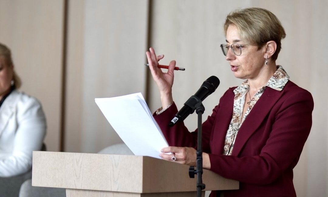 Woman in burgundy blazer speaking at podium with microphone at HEALTHXCHANGE Summit