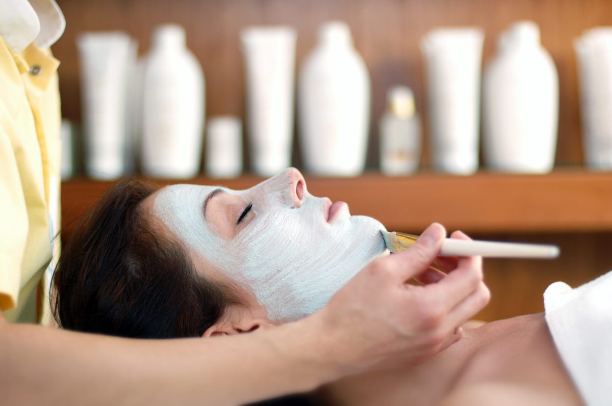 Woman receiving facial treatment with blue clay mask at luxury spa