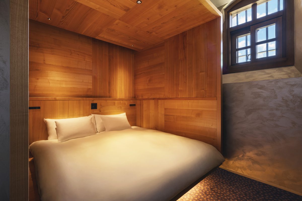 Wooden luxury bedroom with platform bed and large window in converted prison cell