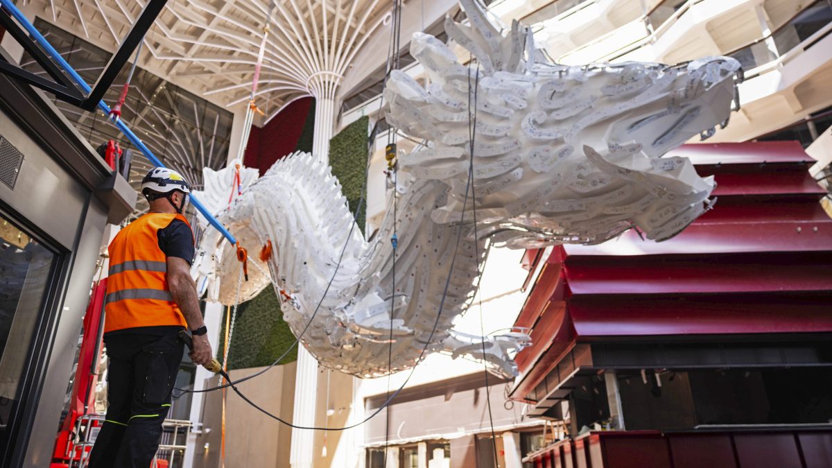 Workers install a massive illuminated 12-metre dragon sculpture aboard MSC World Asia