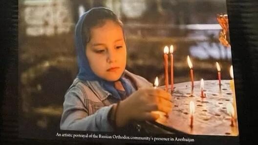 Young girl in traditional headscarf lighting candles in a religious setting