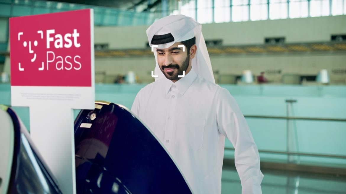 Man in traditional white thobe and ghutra at airport with Fast Pass facial recognition logo