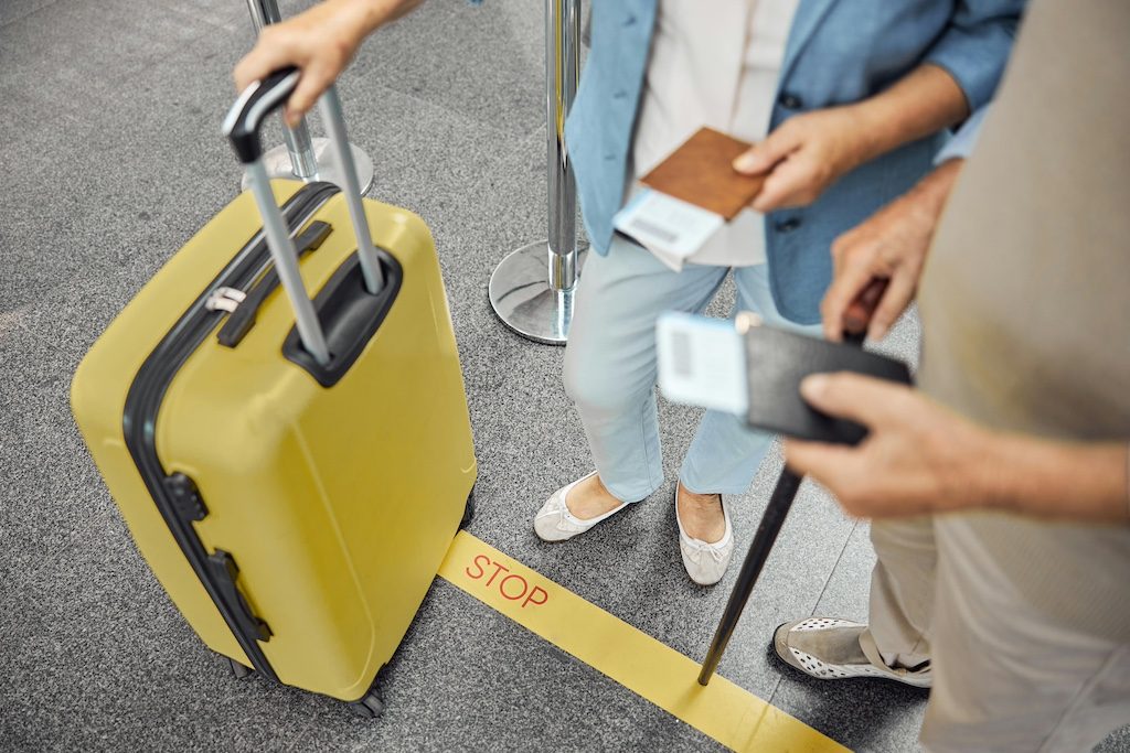 Travelers with luggage and passport at airport, checking travel documents